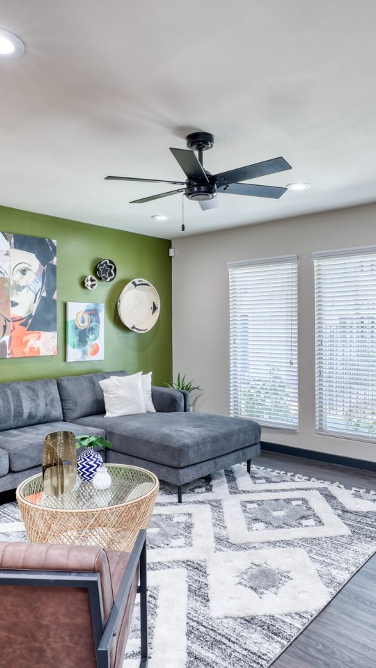 a living room with green walls and a ceiling fan at The  Palmer